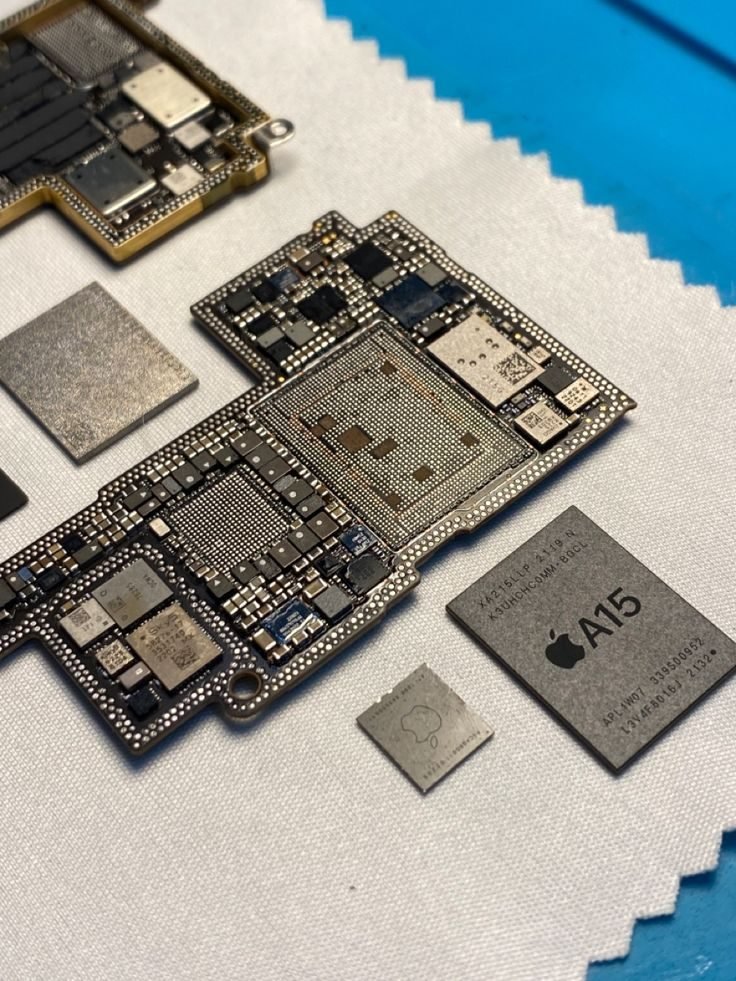 Placa madre de iPhone abierta junto a su chip A15, sobre el paño del laboratorio